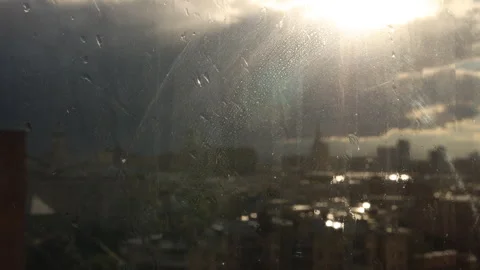 Window overlooking city skyline under dramatic storm clouds, sunlight breaks Stock Footage 339304189