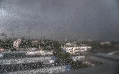Window overlooking the spring-summer rainy city. Glass with fine drops on it. Stock Photos