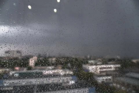 Window overlooking the spring-summer rainy city. Glass with fine drops on it. Stock Photos