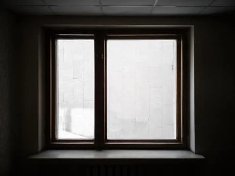 Window overlooking the wall. Silhouette of a window in dark interrior behind  Stock Photos