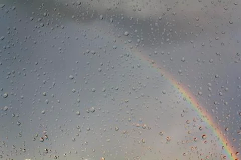 Window with raindrops with rainbow on the background Stock Photos
