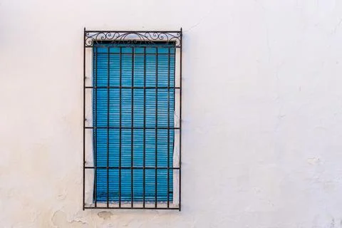 Window with a rectangular shape and blue shutters enclosed with metal bars Stock Photos