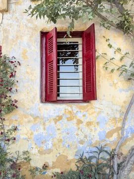 Window with red blinds on old wall with flowers Foto stock