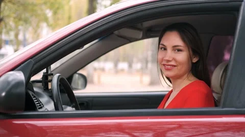 The window of a red car is lowered. Driver beauty in a red dress smiles 스톡 동영상 141562638