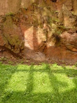 Window reflections on grass and rock face Stock Photos