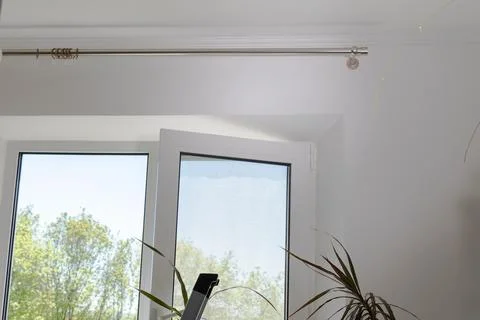 A window in a room shows an empty curtain rod waiting for fresh curtains to.. Stock Photos