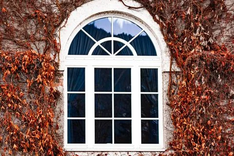 A window with a round arch in a building made of a brick wall around the wind Stock Photos