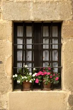 A window of a rustic house with railings and flowerpots Stock Photos