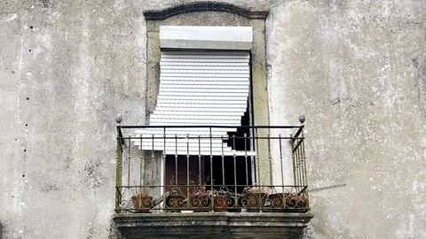 Window with Rusty Iron Balcony and Broken White Roller Shutter, Abandoned House 库存影片 313442526