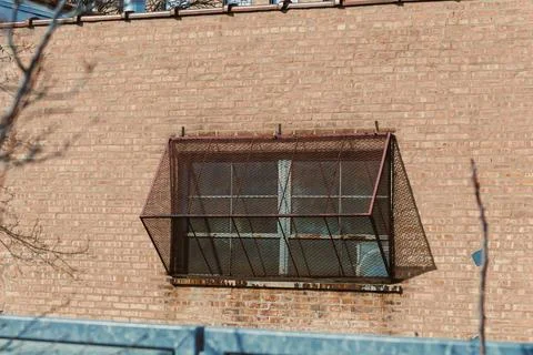 Window security grate on a brick wall in an urban area during daylight hours Stock Photos