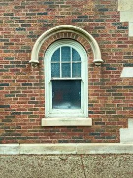 A window is set into a brick wall with an arch above it. The wall has various 写真素材