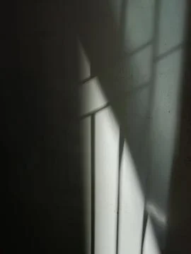 Window shadows create a minimalist abstract composition on the wall. Ideal for b Stock Photos