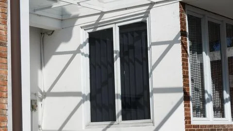 Window with Shadows on a White Wall and Brick Foto stock