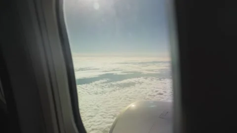 Window shows clouds below, airplane soaring high above Video stock 320359728