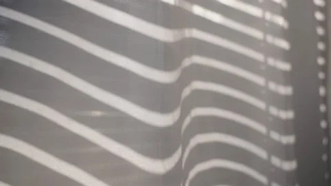 Window shutters or blinds open up creating shadow lines on white curtain Stockbeeldmateriaal 218470103
