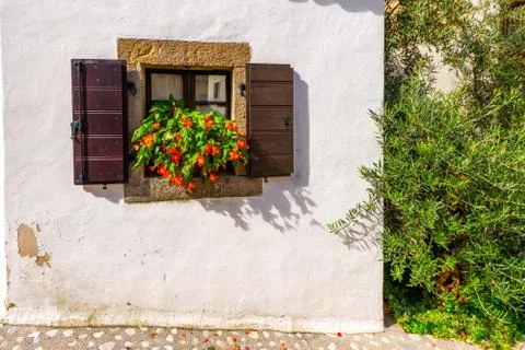 Window with shutters on the rustic stone wall, Mediterranean house with flowers Stock Photos