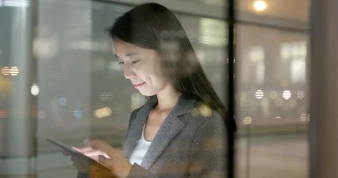 Window though Business woman using tablet computer at night Stock Footage 87646202