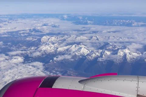 Window view from an airplane on snow capped mountain ranges of the Austrian.. Stock Photos