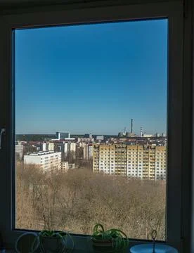 Window view of apartment blocks and red and white smokestacks Stock Photos