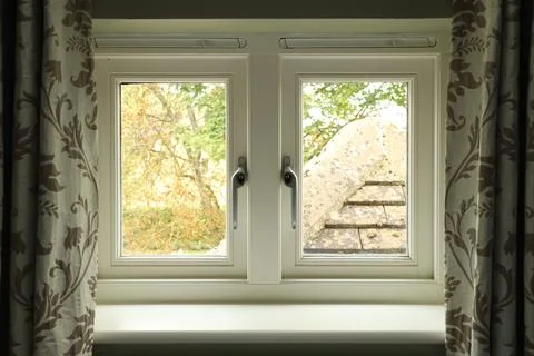 Window view from inside a home looking out to trees and a building roof, cr.. Stock Photos