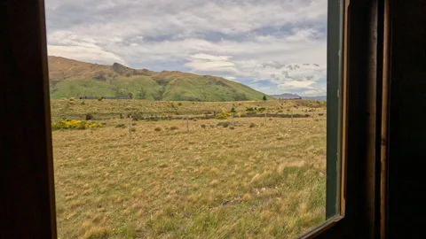 Window view old retro train passing through rural New Zealand countryside. Stock Footage 335737305