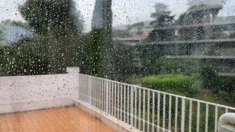 Window view with rain drops to blurred terrace and garden in the rain. Stock Footage 205208996
