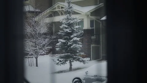 Window view of the snow falling outside on the suburban street in winter Stock Footage 294722694