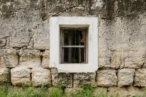Window with white frame on a wall of dusty and rusty stones. Stock Photos