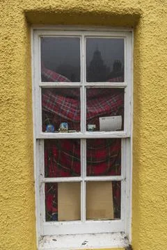 A window in a yellow wall with a red chequered curtain and small objects on the Stock Photos
