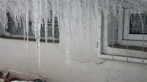 Windows of an abandoned house with melting icicles on the roof Stock Footage 71964294
