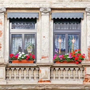 Windows with geranium flower pots, old house facade detail Stock Photos