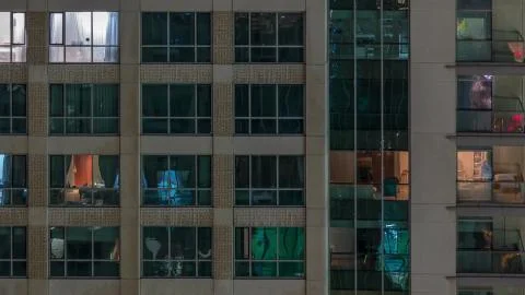 Windows of the multi-storey building with lighting inside and moving people i Stock-Fotos