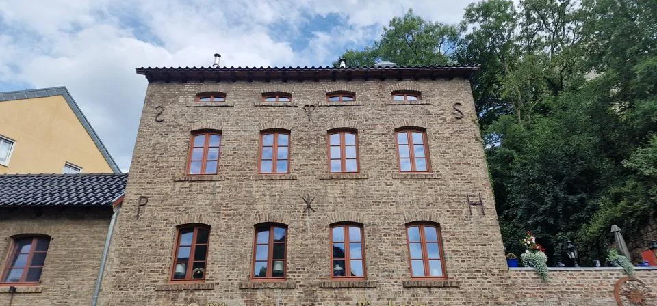 Windows sit in rows on a wall of bricks. Glass reflects the sky and trees. Ro Stock Photos
