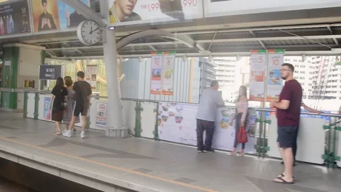 Windows view of BTS Skytrain leaving Nana station with passengers waiting Video stock 115960312