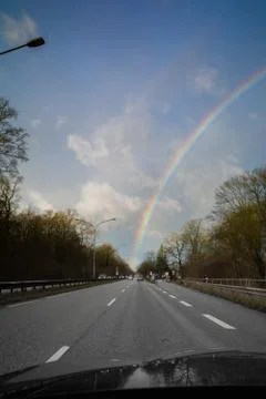 From  windscreen of a moving car you can see a rainbow in the sky Stock Photos