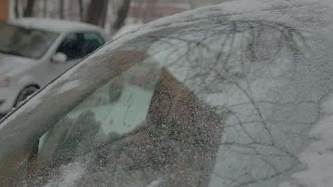 Windshield covered in snow during a winter snowfall in a residential area Stock Footage 316488619