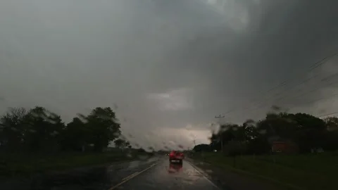Windshield POV driving in heavy rain under dark storm sky, headlights ahead Stock Footage 320002946