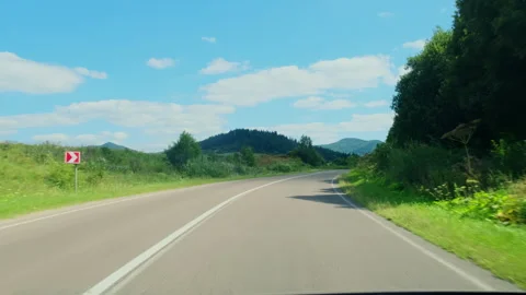 Windshield view mountain road curve toward open hills summer sky Stock Footage 323883511