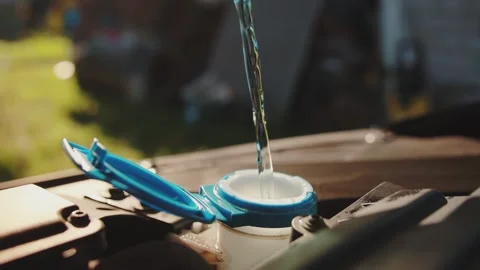 Windshield washer fluid is poured into the windshield wiper reservoir of a car Stock Footage 256201896