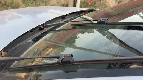 Windshield wipers sweep across dry glass on a silver car, rubber blades moving Stock Footage 337114556