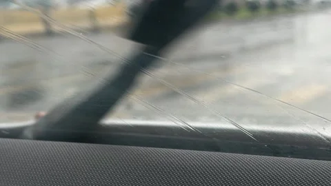 Windshield wipers working on rainy car window with blurred road view, wet Stock Footage 337120660
