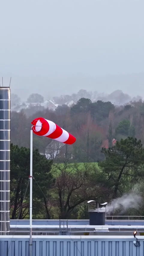 Windsock blowing in the wind on rooftop during cloudy weather. Stock Footage 337689575