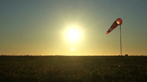 Windsock on blue sky. Red and white wind sock on th wind. Sun shines into lens Stock Footage 148354000
