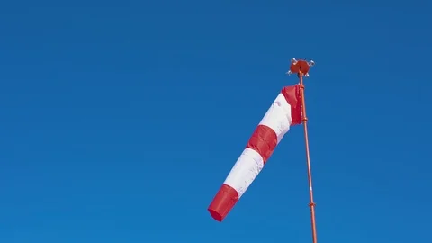 Windsock develops on blue cloudless sky background. Video stock 106090860