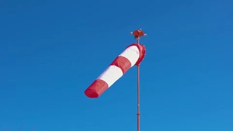 Windsock develops on blue cloudless sky background. 스톡 동영상 106657639