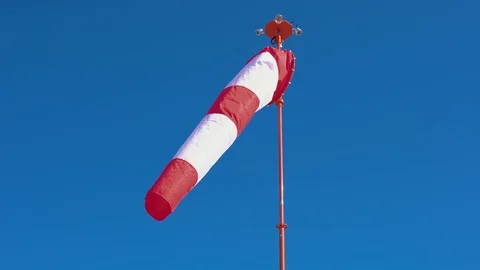 Windsock develops on blue cloudless sky background. Video stock 106657820