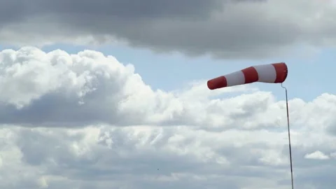 Windsock develops in the wind against the background of a cloudy sky and forest Vidéo 153599933