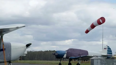 Windsock develops in the wind against the background of a cloudy sky and forest Vidéo 153604233