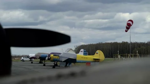 Windsock develops in the wind against the background of a cloudy sky and forest Vidéo 153662755