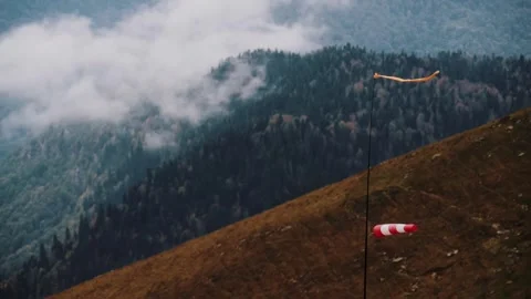 Windsock flapping over misty forested mountain slope Video stock 347734868